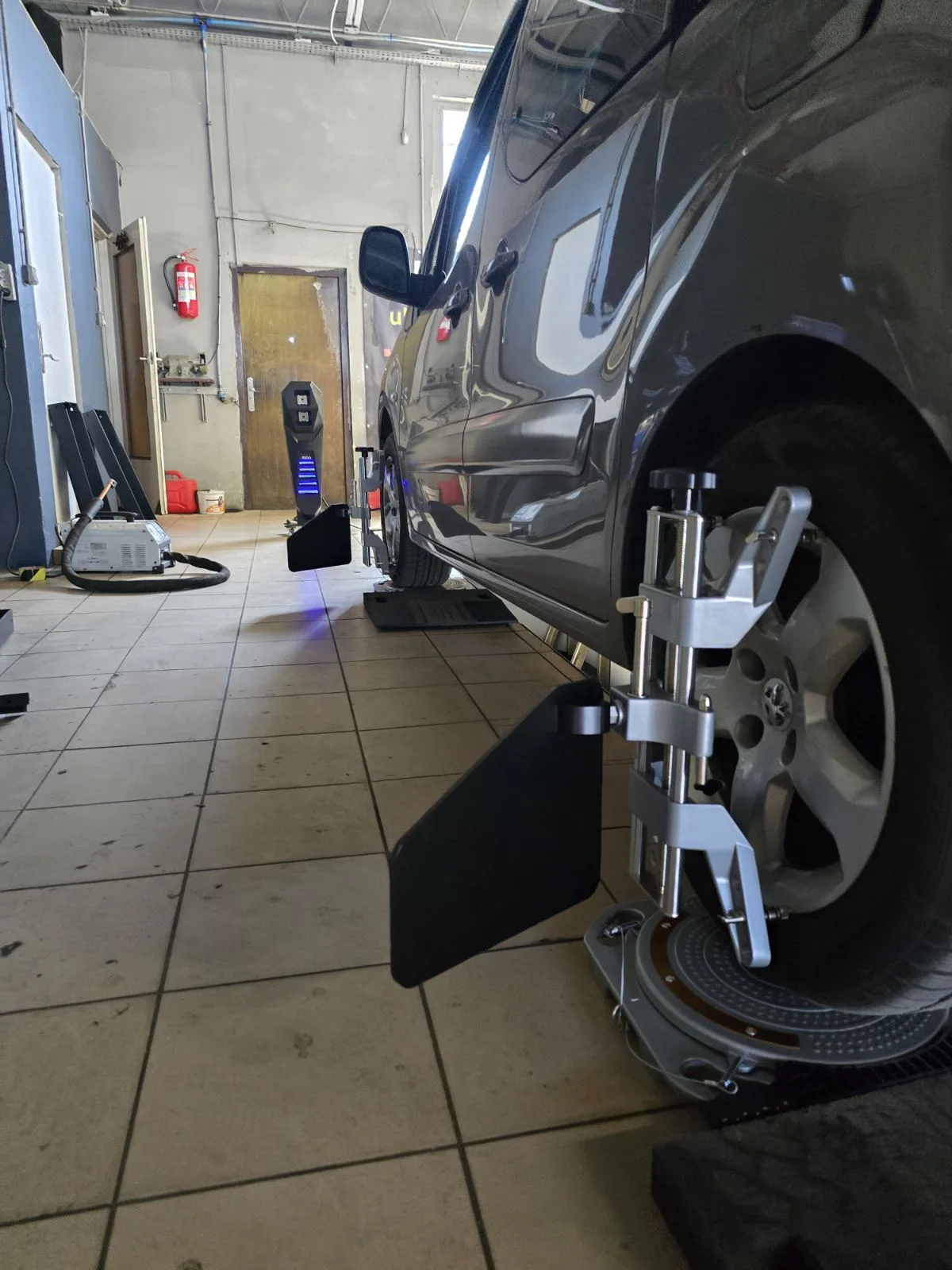 Pomiar geometrii kół 3D od strony pasażera – obejma z targetem FCAR na przednim kole samochodu w Tiger Serwis